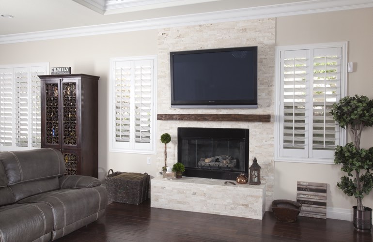 White plantation shutters in a Houston living room with plank hardwood floors.